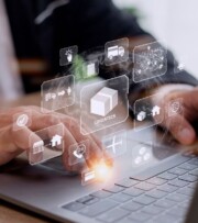 Person using a laptop with digital logistics and supply chain icons, such as shipping, delivery, and warehouse, overlaid on the screen.