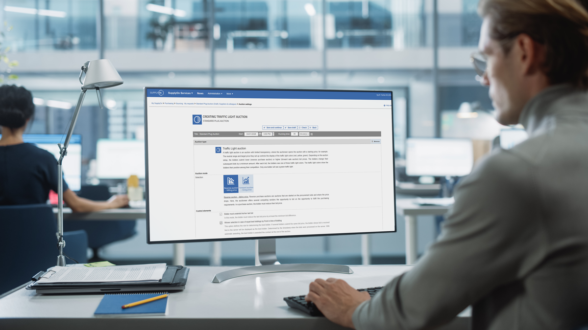 Person sits at a desk in a modern office, viewing a government-related application form on a desktop computer screen.