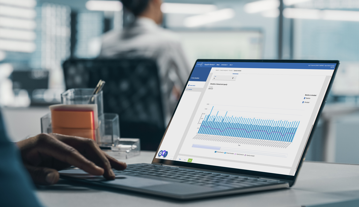 A person works on a laptop displaying a bar chart and data analysis dashboard in an office environment.