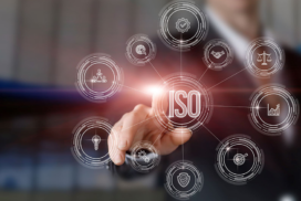 A person in business attire touches a virtual interface with a central ISO icon surrounded by related industry and quality standard symbols.