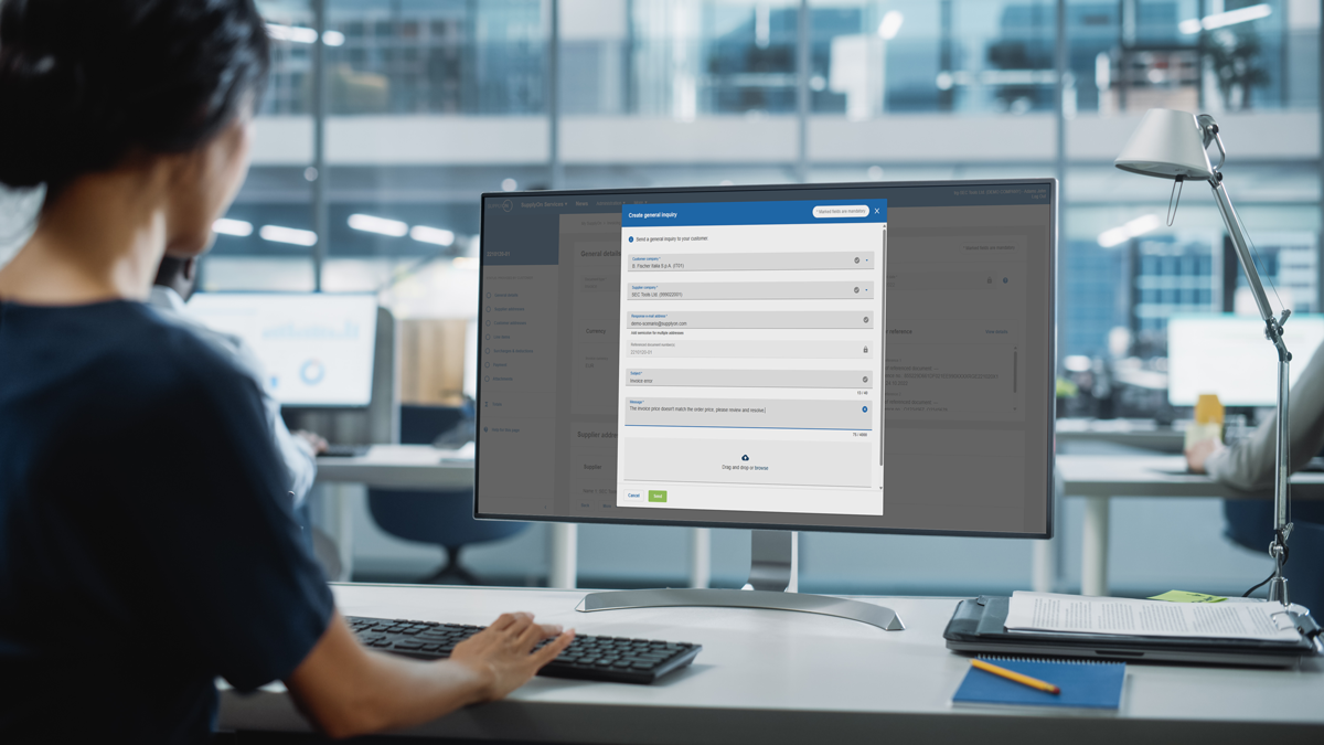 Person sits at a desk in an office, using a computer with an online data input form displayed on the monitor.