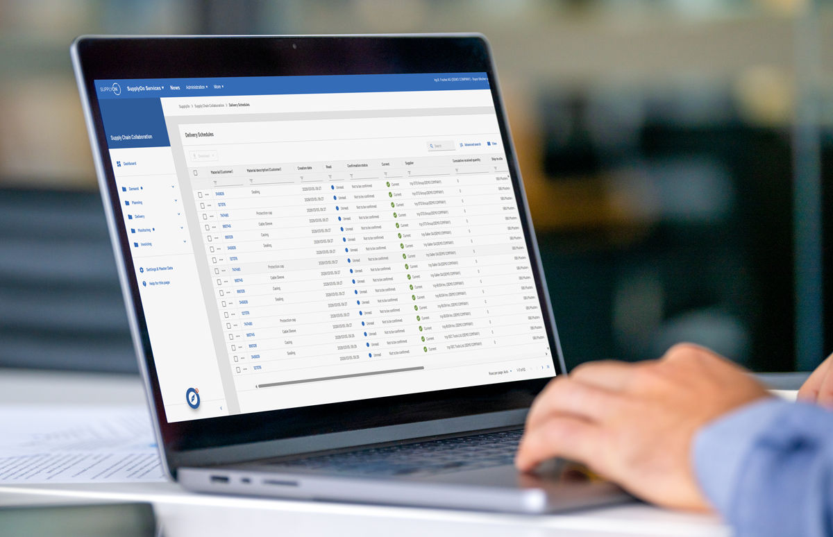 A person using a laptop displaying a data management dashboard with various columns and entries on the screen.