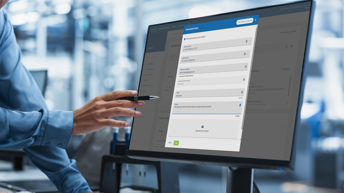 A person points at a computer monitor displaying a data entry form in a professional office or industrial setting.