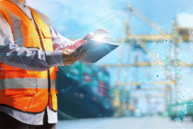 Person in an orange safety vest uses a tablet at a shipping port, with digital network graphics overlaid, suggesting technology in logistics or supply chain management.