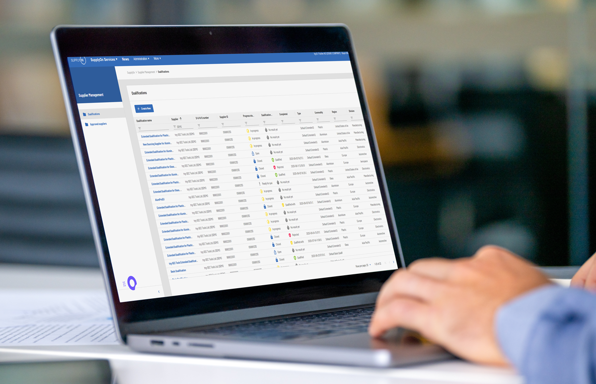 A person uses a laptop displaying a dashboard with a table of user accounts, email addresses, and status indicators in a web-based management system.