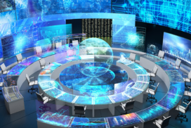 A modern high-tech control room with circular desks, multiple computer monitors, digital screens, and holographic globe projections displaying data and network graphics.