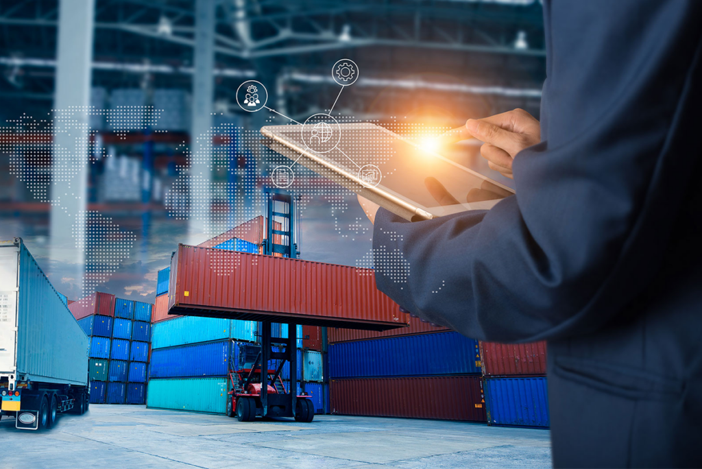 Person using a tablet with digital icons overlaid, in front of stacked cargo containers and a forklift at a warehouse or shipping yard.