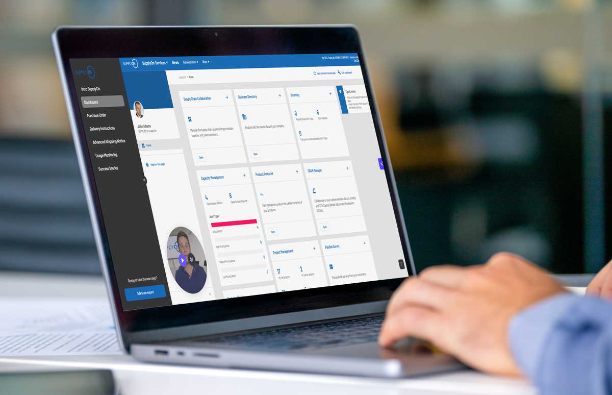 A person uses a laptop displaying a dashboard interface with a sidebar menu and profile information in a modern office setting.